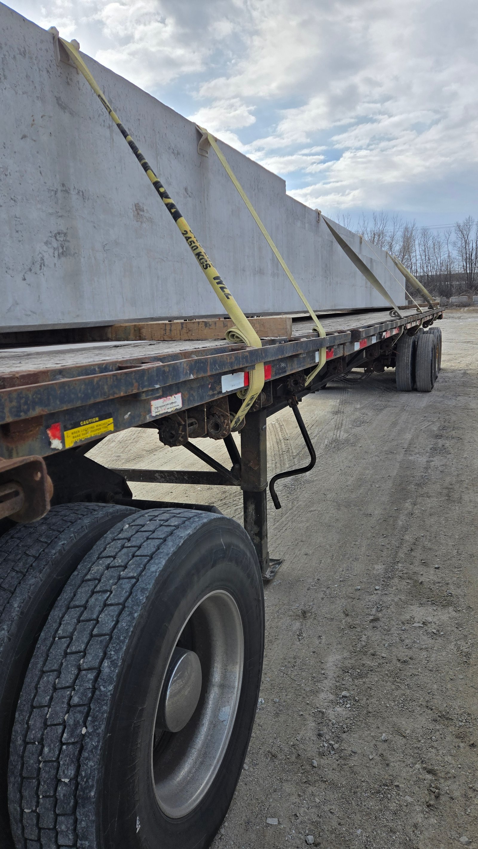 Precast concrete section held by yellow straps on a flatbed trailer